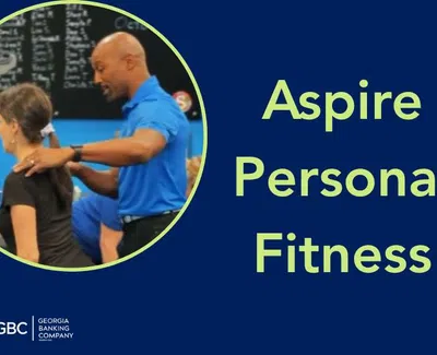 Personal trainer assisting a woman with exercise at Aspire Personal Fitness, Georgia Banking Company logo visible.