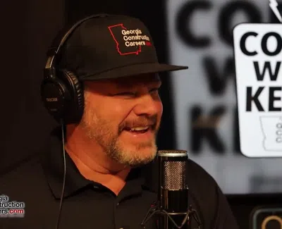 Man wearing Georgia Construction Careers hat and headphones speaking into microphone on Coffee with Kenny podcast.
