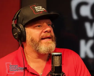 Man with headset and cap speaking into a microphone during a podcast titled Coffee with Kenny.