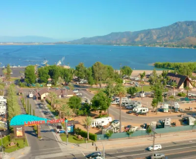 Aerial view of Launch Pointe RV park by a large lake with mountains in the background under a clear sky.