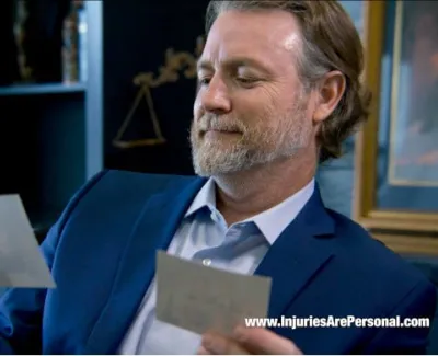 Man in blue suit reviewing papers in an office with legal decor and bookshelves.