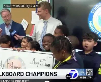 Diverse group of children and adults holding a large check at ABC7 Chalkboard Champions event in school setting.