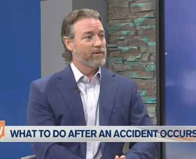 Man in blue suit discusses steps to take after an accident on a TV show set with Suncoast View and ABC 7 logos.