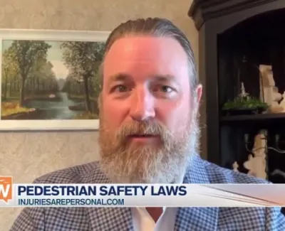 Man with beard in checkered jacket speaking about pedestrian safety laws on a news segment