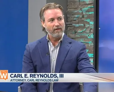 Attorney Carl E. Reynolds III speaking during a Suncoast View interview in a blue suit jacket.