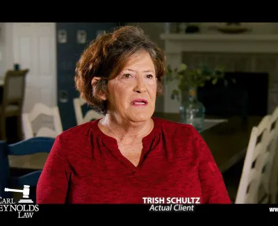 Middle-aged woman in red shirt giving testimonial in a home setting for a law firm advertisement.