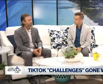 Three news anchors discuss TikTok challenges gone wrong on a modern TV talk show set with ocean backdrop.