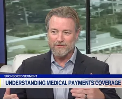 Man in a suit explaining medical payments coverage on a television sponsored segment with informational banner.