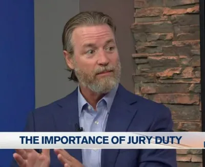 Man in blue suit discussing the importance of jury duty on ABC 7 news segment.