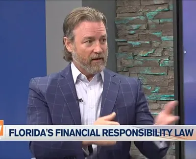 Man with beard in a checkered blue blazer discussing Florida's financial responsibility law on a TV show.