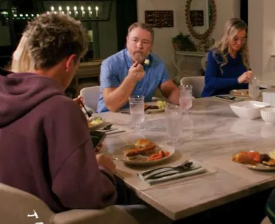 Family gathered around a dining table enjoying a meal together in a cozy home setting.