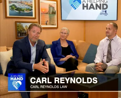 Four professionals seated on a couch discussing with a screen showing A Helping Hand and Carl Reynolds Law logo behind them