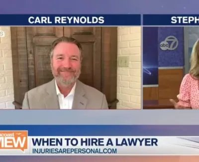 TV interview screenshot with Carl Reynolds and Stephanie Roberts discussing when to hire a lawyer on ABC 7 news.