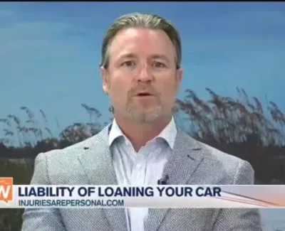 Man in gray blazer discussing liability of loaning your car on Suncoast View TV show with nature background.