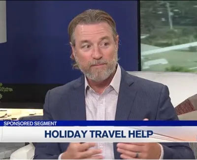Man in suit discussing holiday travel help on a TV news segment with ABC 7 logo and weather info