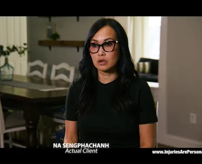 Woman with glasses speaking in a home setting with dining table and chairs in the background