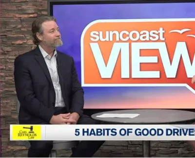 Two hosts discuss driving habits on Suncoast View TV show with a stone wall background and show logo.