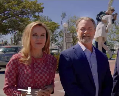 Four professionals in business attire standing outdoors with trees and blue sky in the background