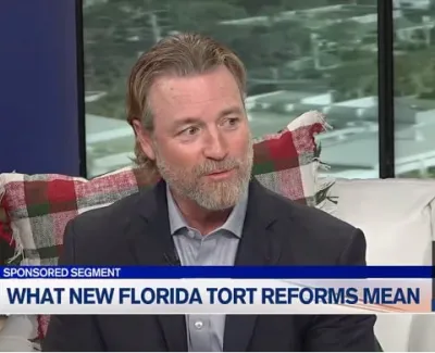 Man in suit discusses Florida tort reforms during a sponsored TV segment with holiday decor in the background.