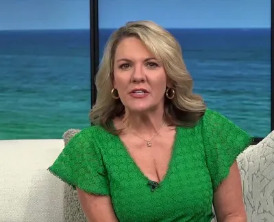 Female TV host in a green dress presenting Suncoast View with ocean backdrop and 9:26 time stamp.