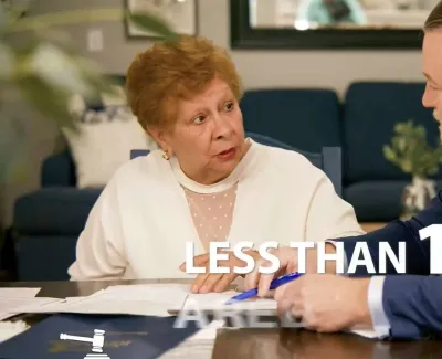Older woman and man in suit discuss documents at a table with text less than 1 percent.