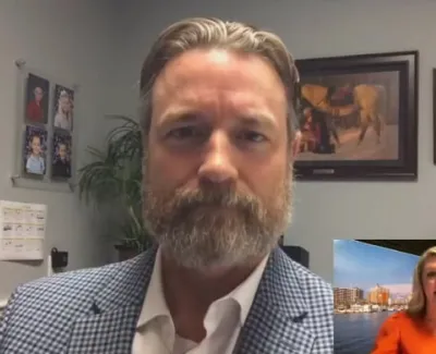 Bearded man in checkered blazer on video call with female news anchor in inset during ABC 7 broadcast.