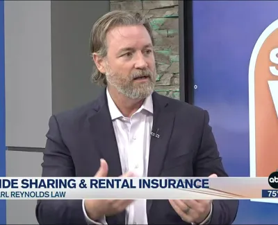 Man in suit discussing ride sharing and rental insurance on a televised news segment with Carl Reynolds Law logo.