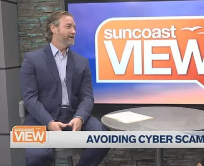 Two hosts discuss avoiding cyber scams on Suncoast View TV show set with modern studio backdrop.