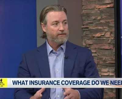 Man in blue suit explaining insurance coverage on a news segment with Carl Reynolds Law banner and ABC 7 logo.