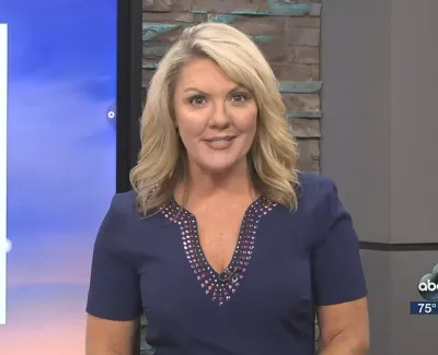 Blonde female news anchor wearing a navy dress presenting live on ABC 7 with weather and time displayed