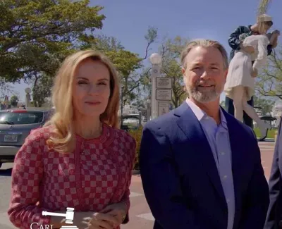 Four business professionals standing outside on a sunny day with trees and a statue in the background.