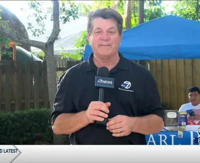 Male news reporter holding microphone outdoors with ABC7 News logo and cooling tips banner