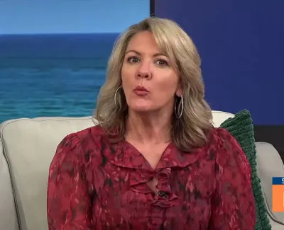 Blonde woman in red blouse speaking on a daytime TV show with ocean backdrop and Suncoast View logo.