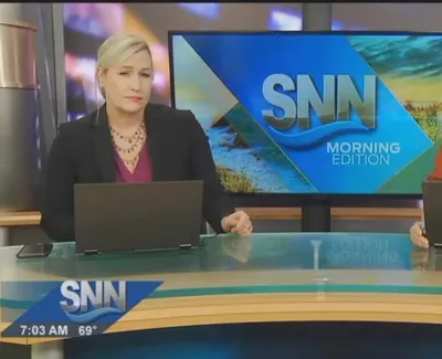 Two female news anchors present SNN Morning Edition at a news desk with laptops and a screen behind them.