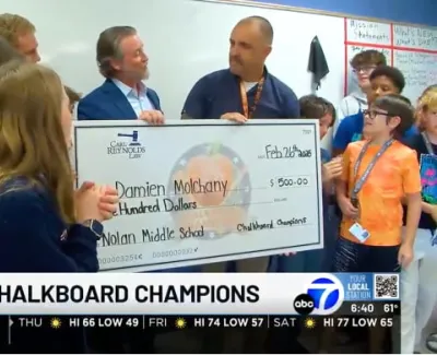 Middle school students and adults holding a large check for $500 presented at a classroom award event