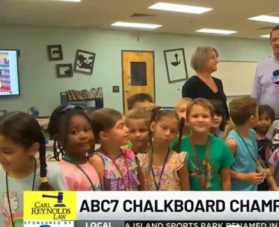 Children and adults in classroom being interviewed by news reporter for ABC7 Chalkboard Champions segment.