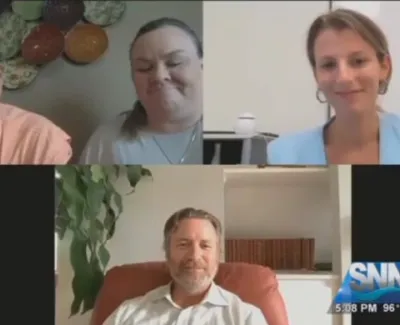 Four people engaged in a virtual video conference with a news channel logo in the corner.