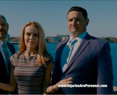 Three professional lawyers standing by waterfront with city skyline, Carl Reynolds Law logo, and website link.