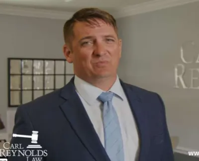 Professional male lawyer in suit standing in office with Carl Reynolds Law logo and website in background