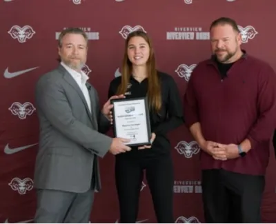 Four people standing in front of Riverview Rams backdrop, one holding an award plaque, smiling for photo.