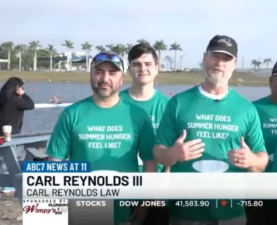 Group of five people wearing green shirts with 'What does summer hunger feel like?' text outdoors near water.