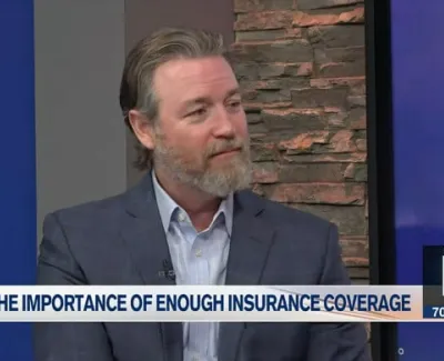 Man in suit discussing the importance of sufficient insurance coverage in a TV interview setting.