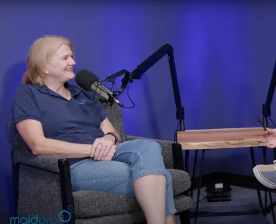 Two people engaged in a podcast conversation with microphones in a studio featuring a blue background.