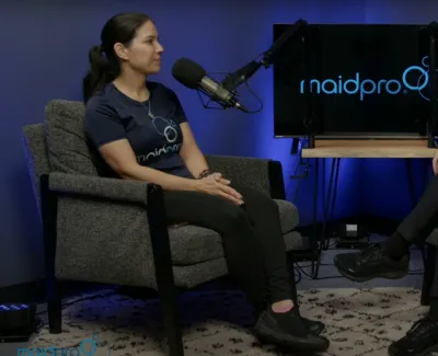 Two women in MaidPro shirts sitting in armchairs recording a podcast with MaidPro logo on screen behind them.
