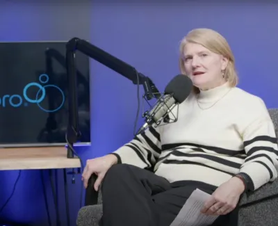 Two women engaged in a podcast recording with microphones and a screen displaying Maidpro logo in background.