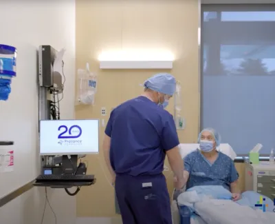 Orthopedic doctor in scrubs consulting a seated patient in a modern clinic room with Proliance logo visible.