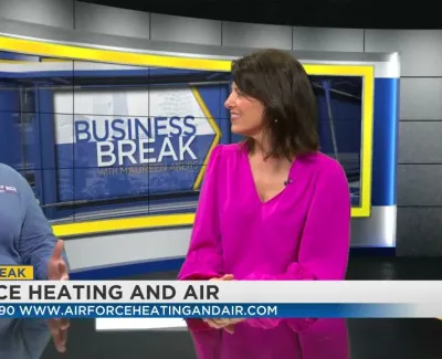 Two women discussing AirForce Heating and Air on a Business Break TV segment with contact details displayed