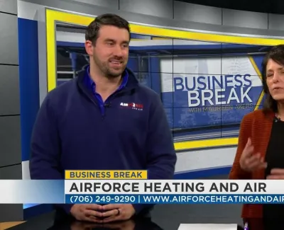 Two hosts on Business Break show discussing Airforce Heating and Air services with contact info on screen.