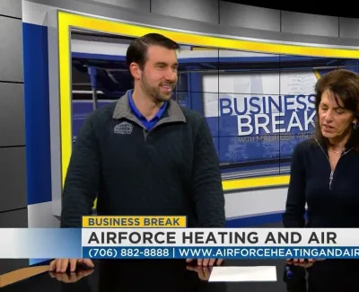 Two hosts talk on the set of Business Break with Airforce Heating and Air ad displayed on screen.