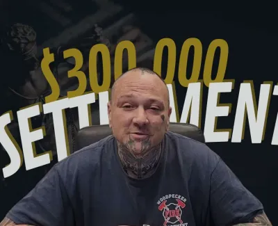 Man with tattoos wearing Woodpecker Fire Department shirt in front of $300,000 settlement text.